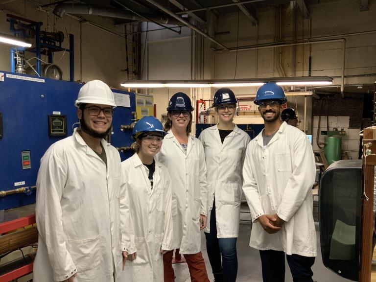 Five students in hard hats and lab coats.
