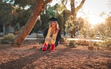 Alejandra Castillo '22 at Old Main at Sunset wearing graduation cap and gown