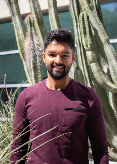 akash Anil Kolekar wearing a maroon shirt and standing in front of a cactus on UArizona Campus