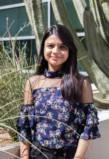 Bhumi Chitroda wearing a black and flowered shirt and standing in front of a cactus on UArizona Campus