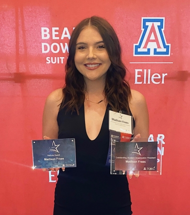Madison in black pantsuit posing against red background and holding Eller Outstanding Student Organization President Award and Nebula Award Madison in black pantsuit posing against red background and holding Eller Outstanding Student Organization President Award and Nebula Award