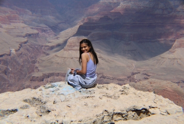 Ananya is seated on a rock overlooking the Grand Canyon.