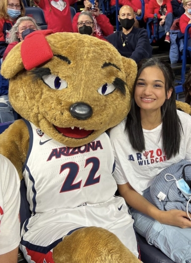 Ananya at a University of Arizona basketball game, seated next to school mascot Wilma Wildcat. 